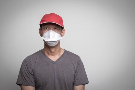 Asian man in red hat wearing surgical  mask to prevent flu virus and  PM2.5 dust air pollution on white backgroundの写真素材