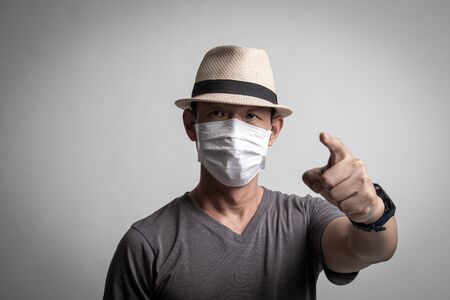 Asian man  wearing surgical  mask to prevent flu virus and  PM2.5 dust air pollution on white backgroundの写真素材