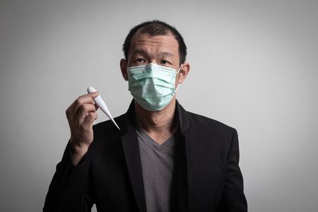 Sick Asian man  wearing surgical  mask to prevent flu virus and  PM2.5 dust air pollution on white backgroundの写真素材
