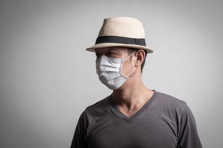 Asian man  wearing surgical  mask to prevent flu virus and  PM2.5 dust air pollution on white backgroundの写真素材