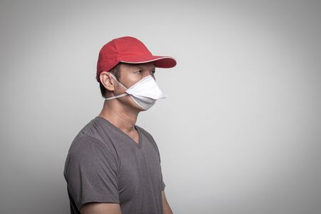 Asian man in red hat wearing surgical  mask to prevent flu virus and  PM2.5 dust air pollution on white backgroundの写真素材