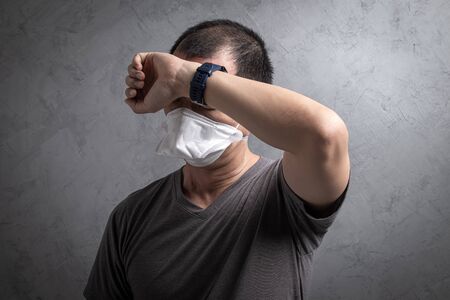 Sick Asian man wearing surgical  mask to prevent flu virus and  PM2.5 dust air pollution  on gray concrete backgroundの写真素材