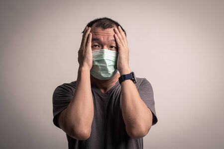 Panic Asian man wearing surgical  mask to prevent flu virus and  PM2.5 dust air pollution on white backgroundの写真素材