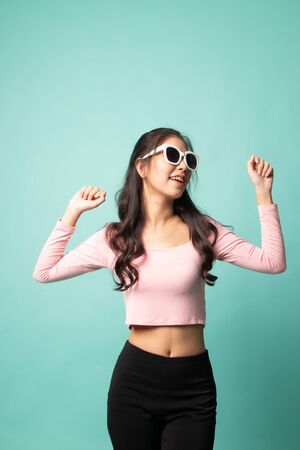 Portrait of a beautiful young asian girl in sunglasses on cyan backgroundの写真素材