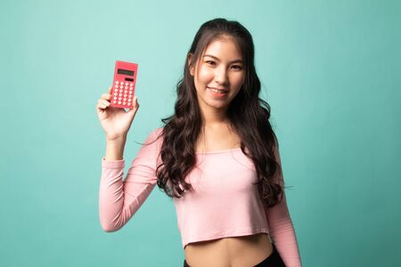 Asian woman smile with calculator on cyan backgroundの写真素材