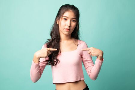 Young Asian woman point at herself ask why me on cyan backgroundの写真素材