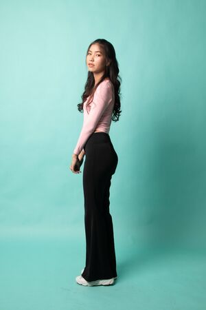 Side Full body of beautiful young asian woman on cyan backgroundの写真素材