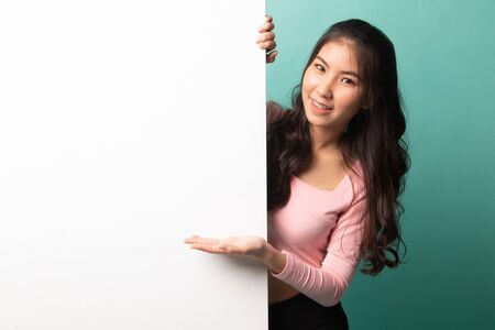 Young Asian woman present blank sign with palm hand on cyan backgroundの写真素材