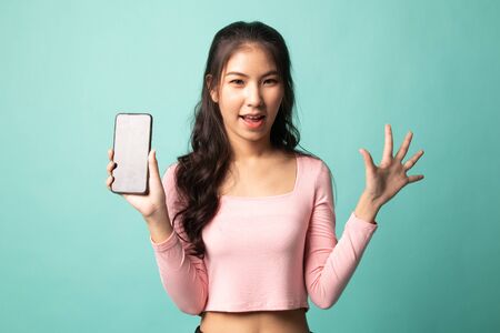 Young Asian woman with mobile phone on cyan backgroundの写真素材