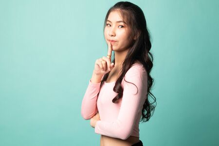 Asian girl show quite hand sign on cyan backgroundの写真素材