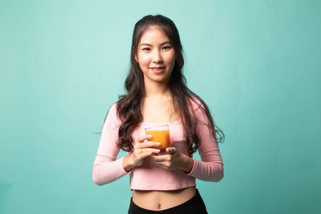 Young Asian woman drink orange juice on cyan backgroundの写真素材