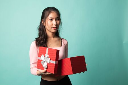 Young Asian woman open a gift box on cyan backgroundの写真素材