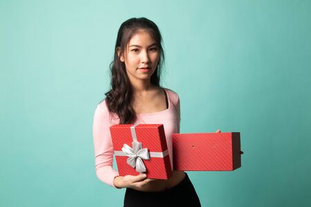Young Asian woman open a golden gift box on cyan backgroundの写真素材