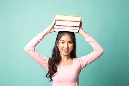 Young Asian woman studying  with may books on cyan backgroundの写真素材