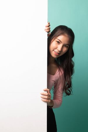 Young Asian woman with blank sign on cyan backgroundの写真素材