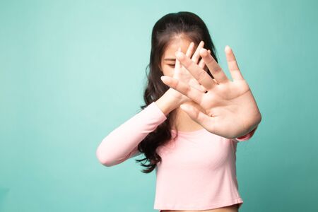 Young Asian woman hide her  face on cyan backgroundの写真素材