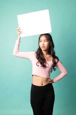 Young Asian woman with white blank sign on cyan backgroundの写真素材