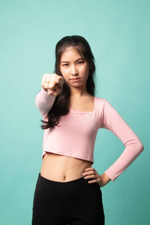 Young Asian woman angry and point to camera on cyan backgroundの写真素材
