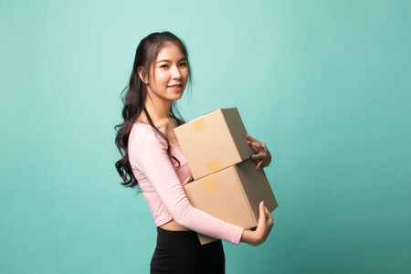 Delivery, relocation and unpacking.  young asian woman holding cardboard box on cyan backgroundの写真素材