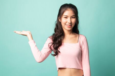 Beautiful young Asian woman show palm hand on cyan backgroundの写真素材