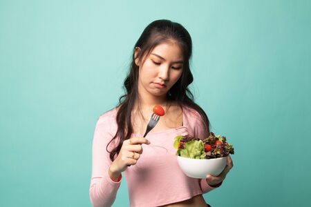 Asian woman hate salad on cyan backgroundの写真素材