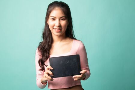 Young Asian woman with a computer tablet on cyan backgroundの写真素材