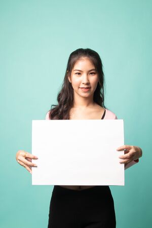 Young Asian woman with white blank sign on cyan backgroundの写真素材