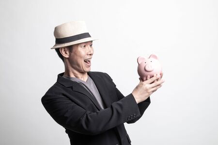 Adult Asian man with a pig coin bank on white backgroundの写真素材
