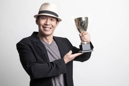 Successful Adult Asian man  holding a trophy on white backgroundの写真素材