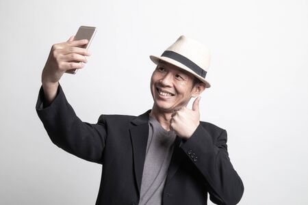 Young Adult Asian man  selfie with mobile phone on white backgroundの写真素材