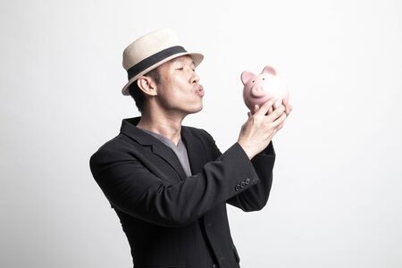 Adult Asian man kiss  a pink coin bank on white backgroundの写真素材
