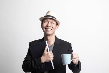 Adult Asian man with a book and cup of coffee on white backgroundの写真素材