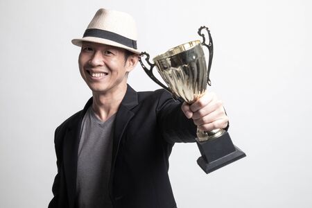 Successful Adult Asian man   holding a trophy on white backgroundの写真素材