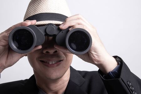Adult Asian man  with binoculars on white backgroundの写真素材
