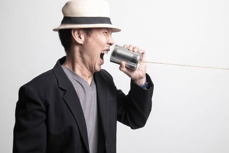 Angry Adult Asian man  shout with tin can phone on white backgroundの写真素材