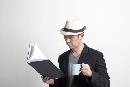 Adult Asian man  with a book and cup of coffee on white background