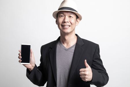 Adult Asian man show thumb up  with mobile phone on white backgroundの写真素材