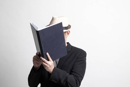 Adult Asian man with a book cover her face on white backgroundの写真素材