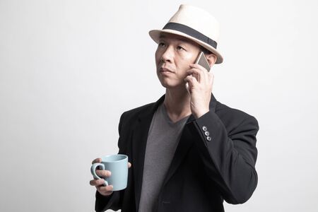Young Asian woman with mobile phone and coffee cup on white backgroundの写真素材