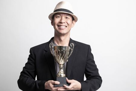 Successful Adult Asian man  holding a trophy on white backgroundの写真素材