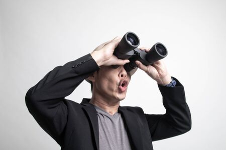 Adult Asian man with binoculars on white backgroundの写真素材