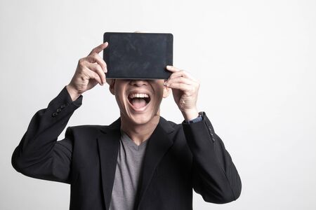 Adult Asian man  with a computer tablet over her face on white backgroundの写真素材