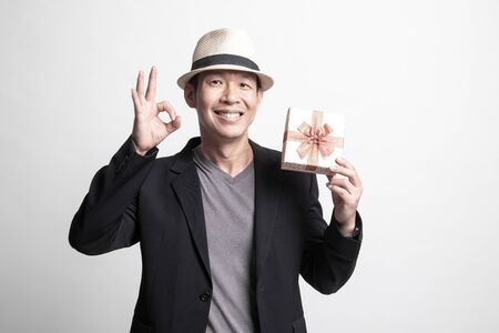 Adult Asian man show OK with a gift box on white backgroundの写真素材