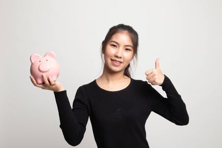 Asian woman thumbs up with pig coin bank on white backgroundの写真素材