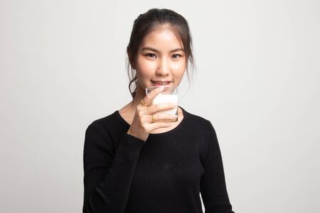 Healthy Asian woman drinking a glass of milk on white backgroundの写真素材