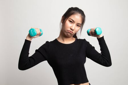 Exhausted Asian woman with dumbbells on white backgroundの写真素材
