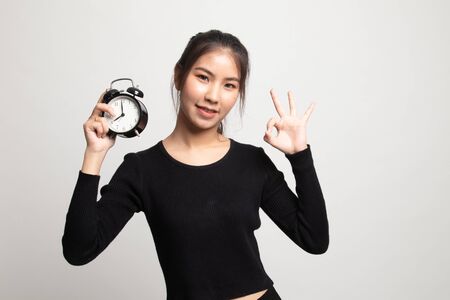 Young Asian woman show OK with a clock on white backgroundの写真素材