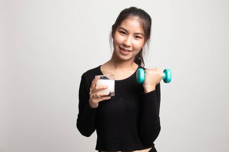 Healthy Asian woman drinking a glass of milk and dumbbell on white backgroundの写真素材