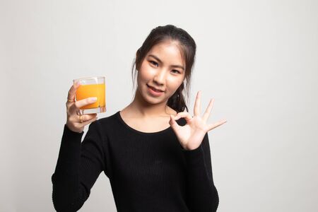 Young Asian woman show OK drink orange juice on white backgroundの写真素材