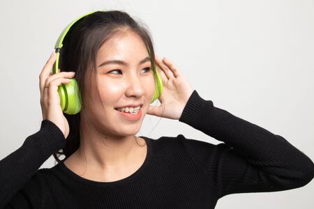 Pretty asian girl listening music with her headphones on white backgroundの写真素材
